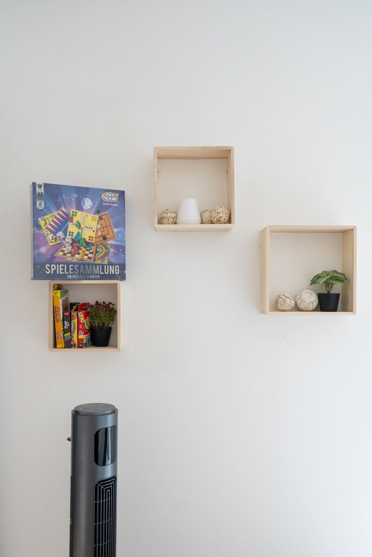 A wall with three wooden shelves, each containing different items.