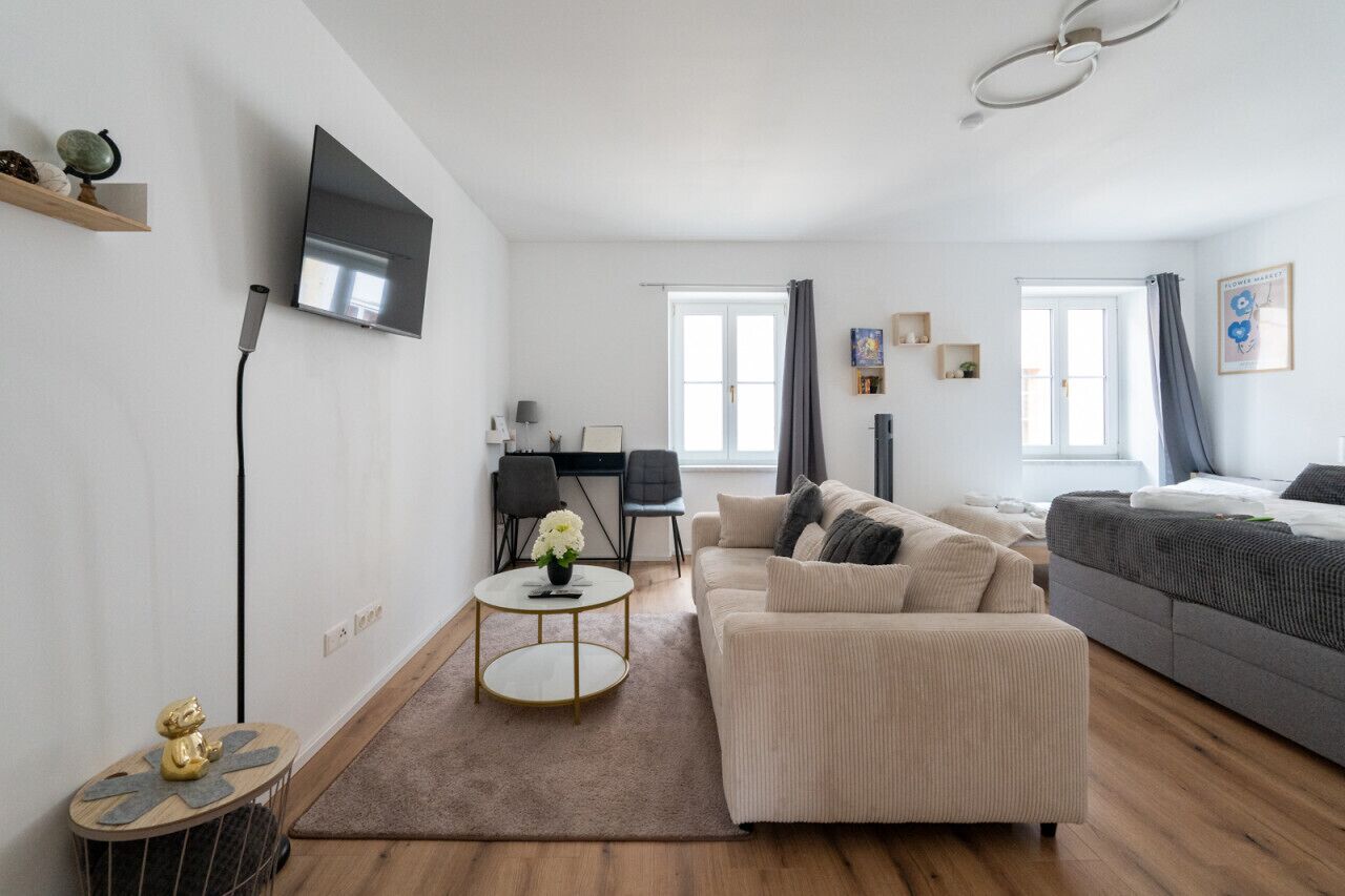 Een moderne woonkamer met een bank, een salontafel, een televisie en een eethoek.