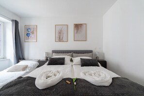 Ein modernes Hotelzimmer mit einem großen Bett, zwei Nachttischen, einem Fenster mit Vorhängen und gerahmten Kunstwerken an der Wand.