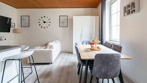 Une cuisine moderne avec un plafond en bois, un coin repas avec une table et des chaises, un canapé et un réfrigérateur.