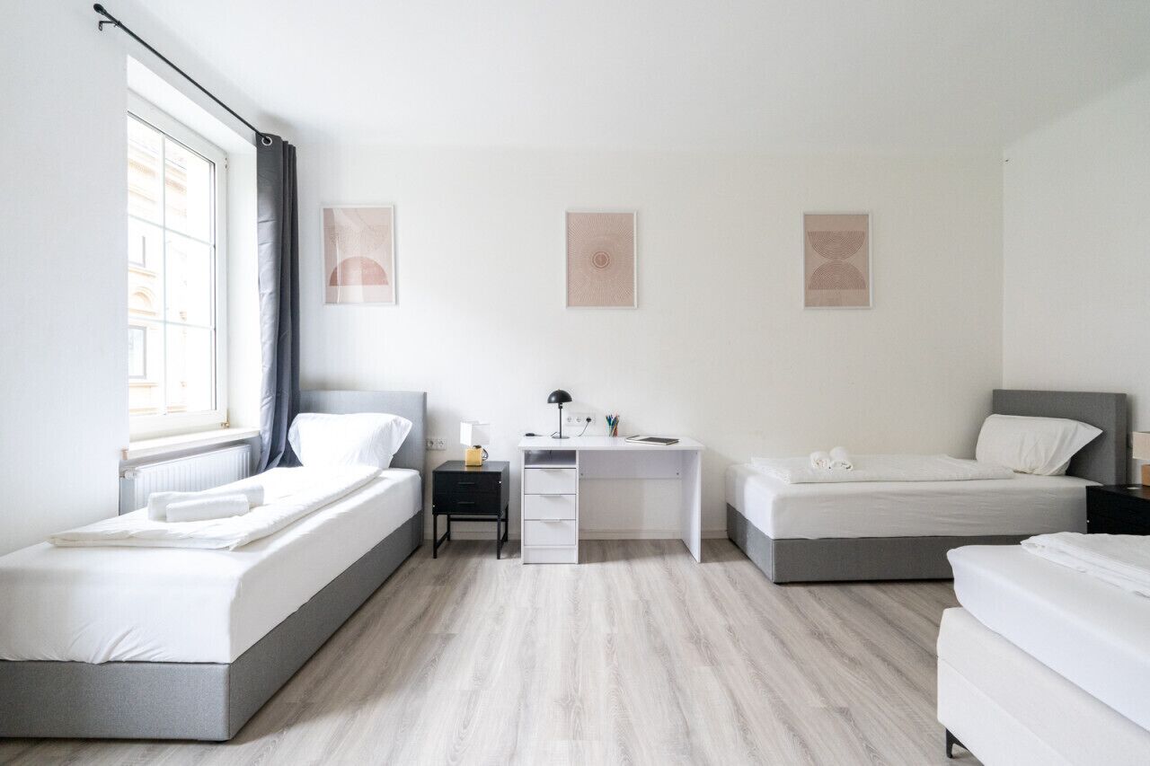 Un dormitorio moderno con dos camas, un escritorio y una ventana.