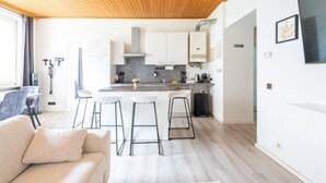Une cuisine moderne avec des meubles blancs, un plafond en bois et un coin bar équipé de tabourets.
