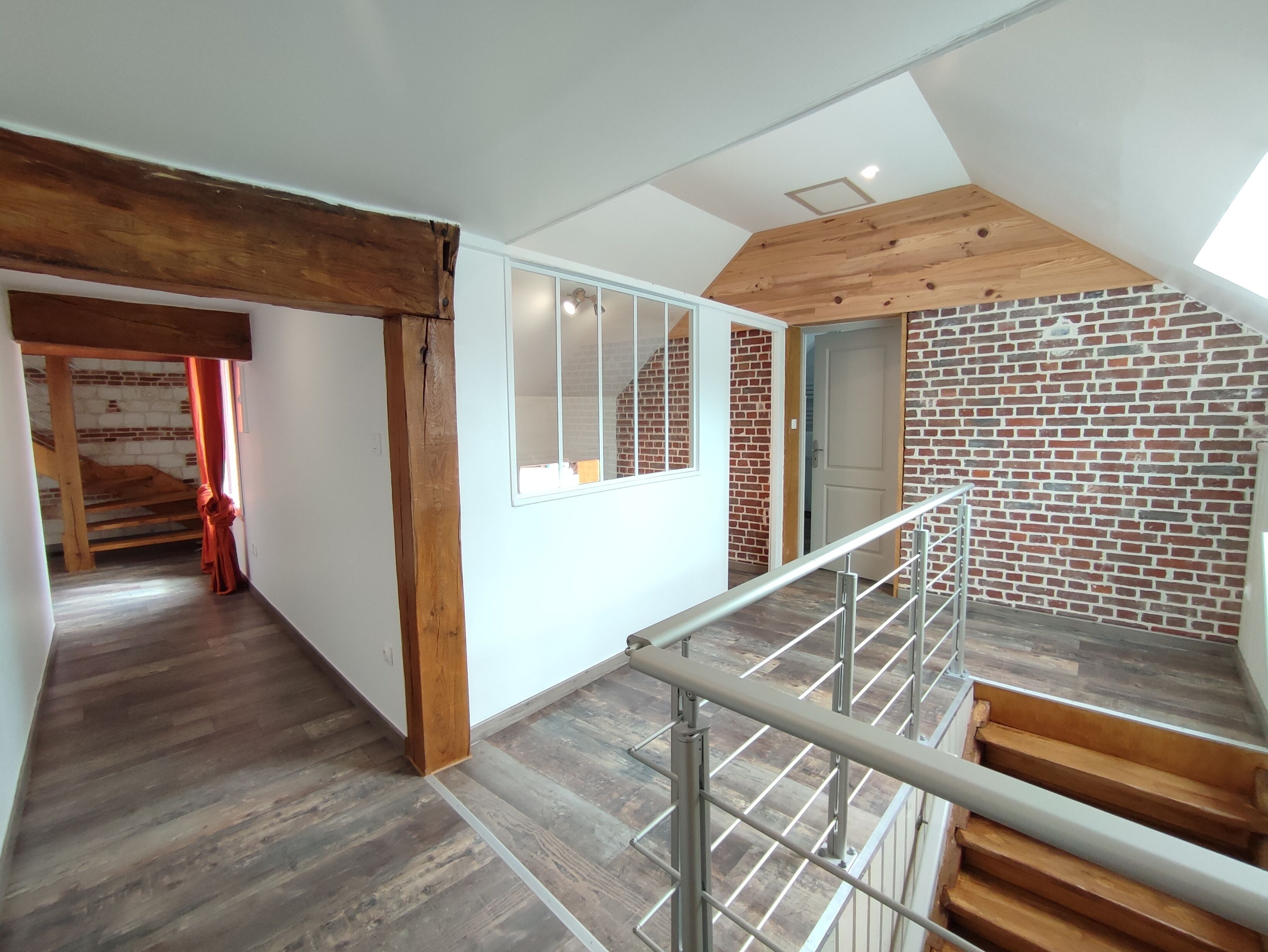 Un intérieur moderne avec un escalier en bois, un mur en briques et une lucarne.