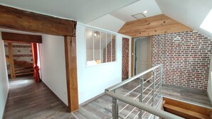 Un interior moderno con una escalera de madera, un muro de ladrillo y un tragaluz.