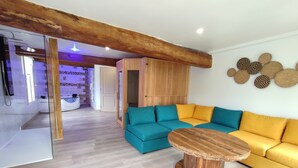 Una sala de estar moderna con techo de madera, un sofá color turquesa con cojines amarillos y una mesa de centro de madera.