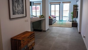 A modern interior with a kitchen area, a dining space, and a living room with a sofa and a TV.