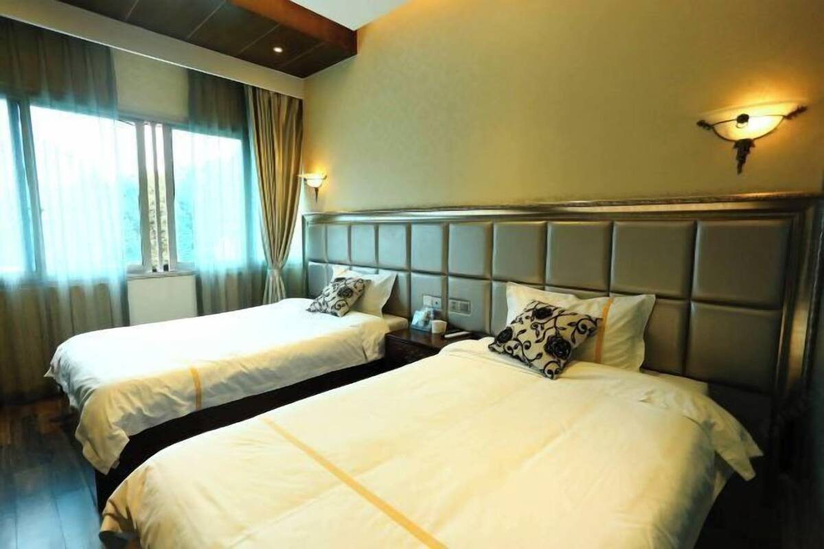 A hotel room with two beds, each with a headboard and pillows.