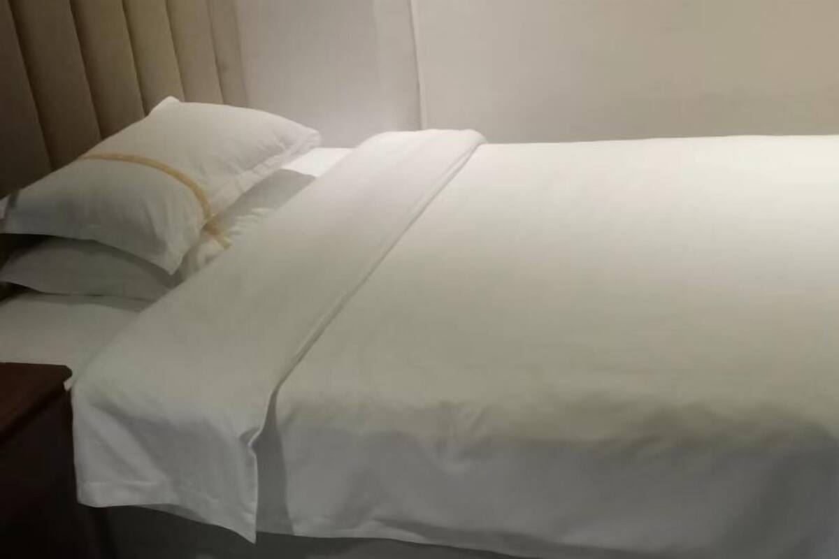 A neatly made bed with white bedding and a headboard.