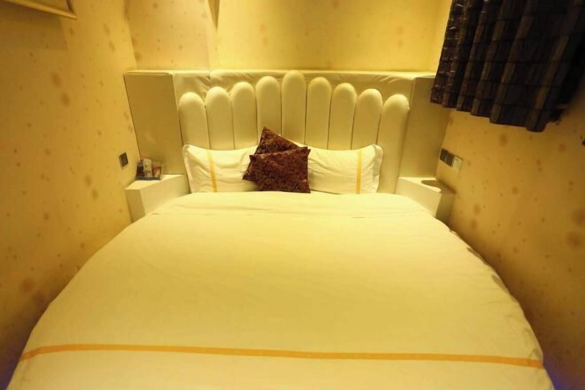 A hotel room with a large bed, white headboard, and two bedside tables.