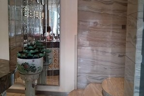 A reception area with a marble wall, a decorative fountain, and a glass partition. - Mingyang Holiday Hotel (Zitong)