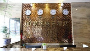 A reception desk with a mosaic wall and clocks, a potted plant, and a framed picture. - Mingyang Holiday Hotel (Zitong)