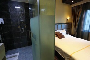 Une chambre d’hôtel comprenant un lit, un espace douche et une cloison en verre.