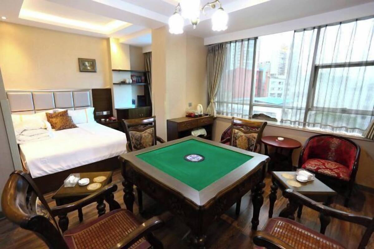A hotel room with a bed, a pool table, a desk, and a chair.