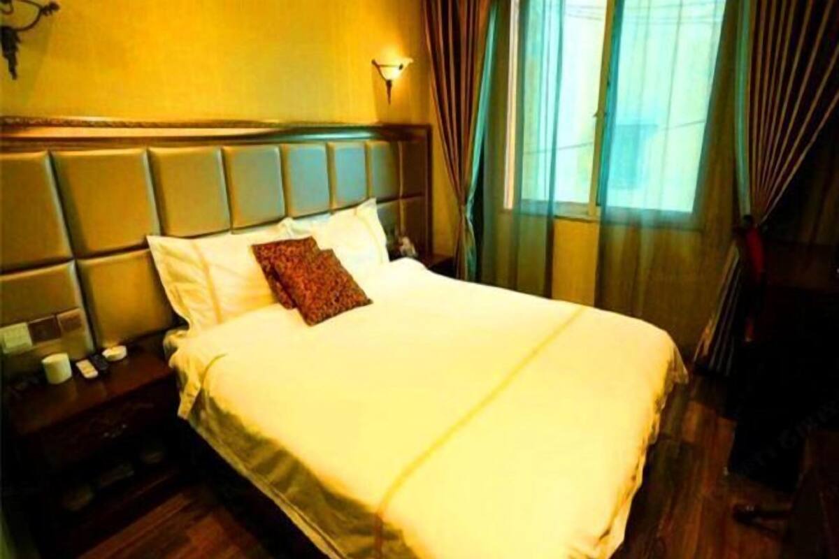 A hotel room with a large bed, a nightstand, and a window with curtains.