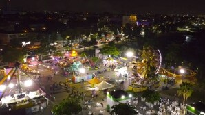 Ein belebtes Open-Air-Festival bei Nacht mit verschiedenen Attraktionen und einer Menschenmenge.