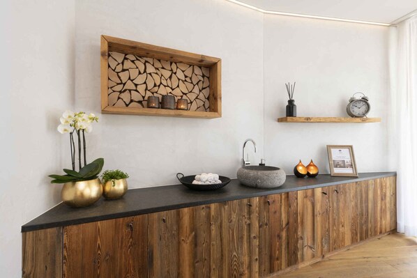 A reception area with a wooden counter, a stone sink, a framed certificate, and decorative items.