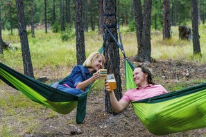 Twee personen ontspannen in hangmatten in een bebost gebied.