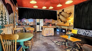 Un intérieur rustique avec une table à manger en bois, des chaises, un coin bar et un canapé.