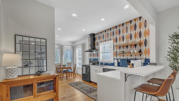 Uma cozinha moderna com ilha central, armários de madeira e backsplash estampado.