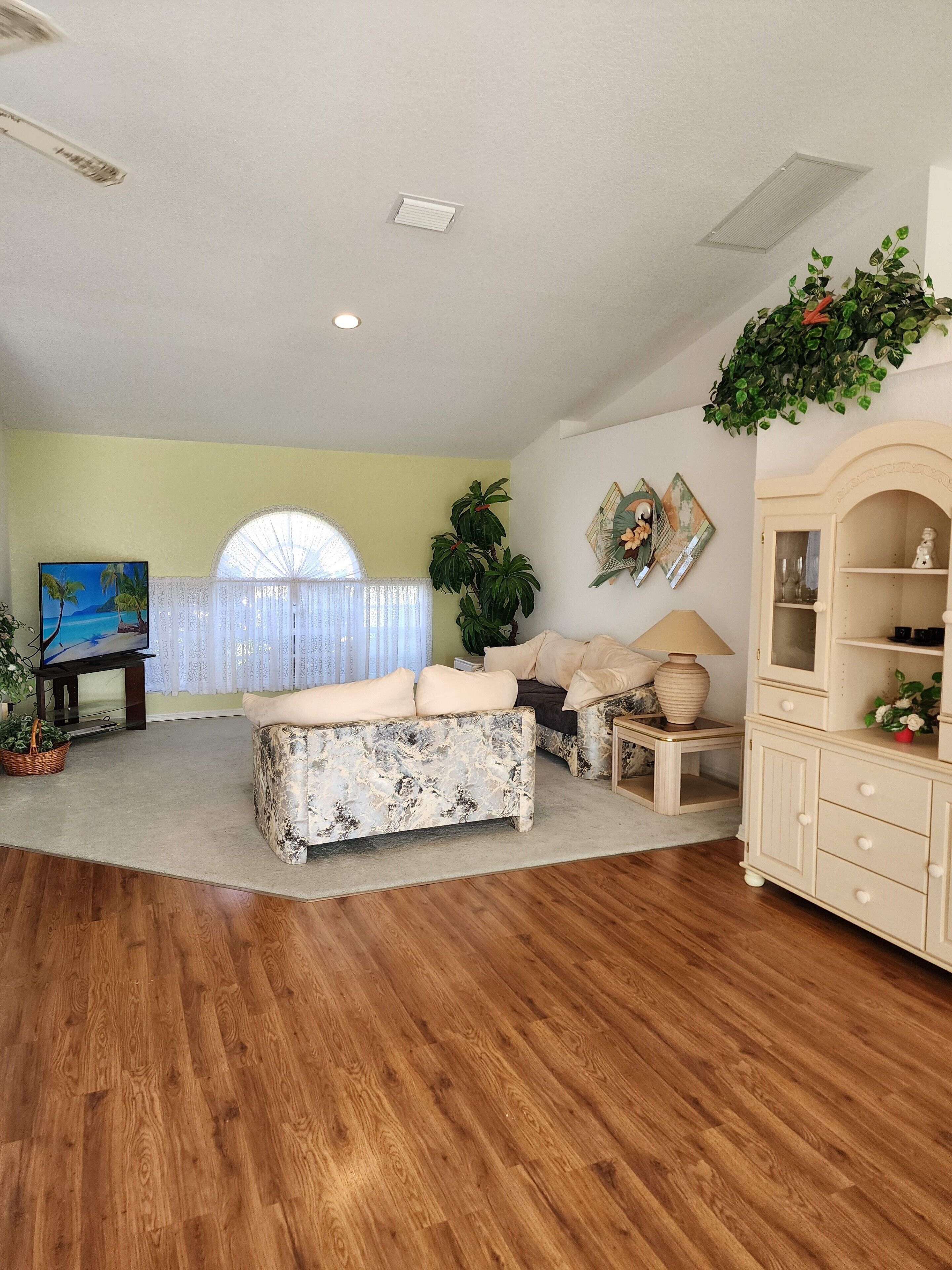 A living room with a wooden floor, a sofa, a TV, and a cabinet.
