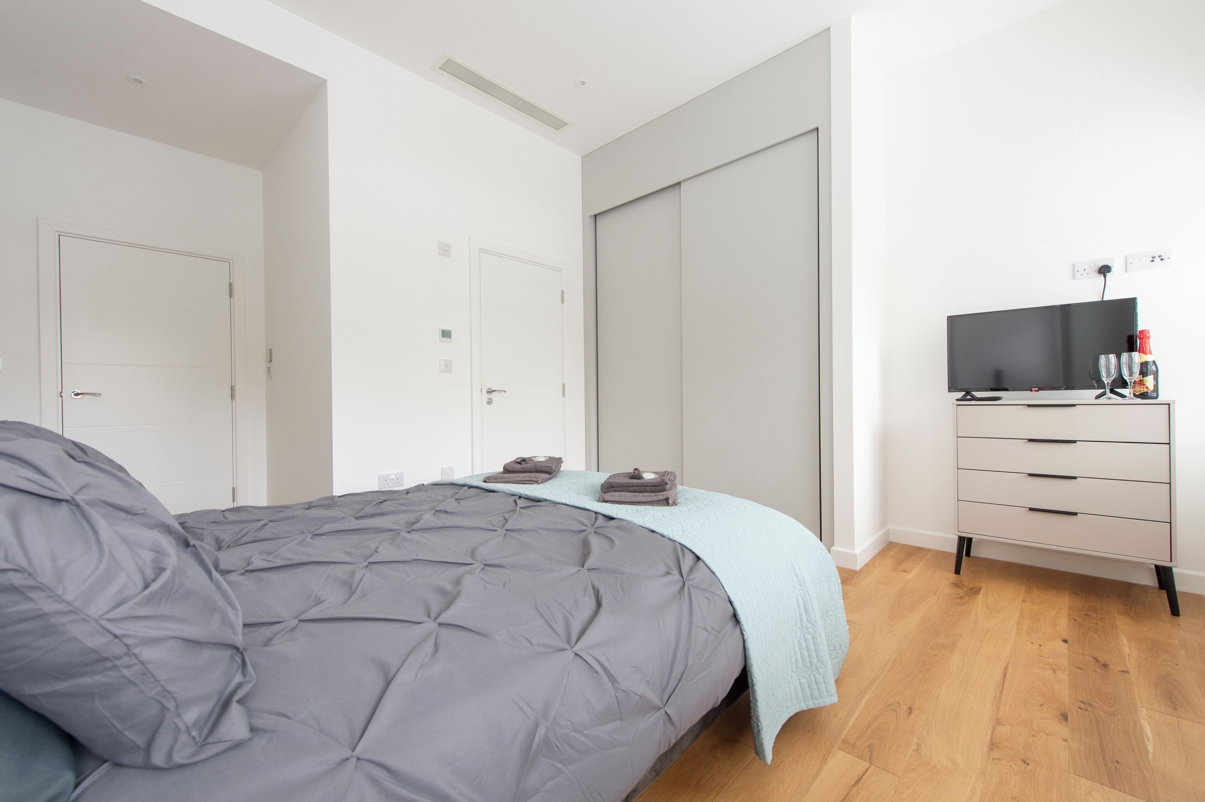 A bedroom with a bed, a dresser, a television, and a closet.