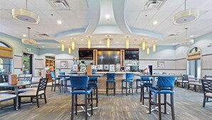 A spacious restaurant with high ceilings, modern pendant lighting, and a central bar area. - House near Disney world and many other attractions and theme parks. (Davenport)