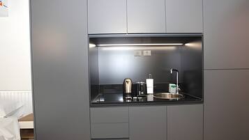 Eine kleine Küchenzeile mit Kaffeemaschine, Wasserkocher und Spüle.