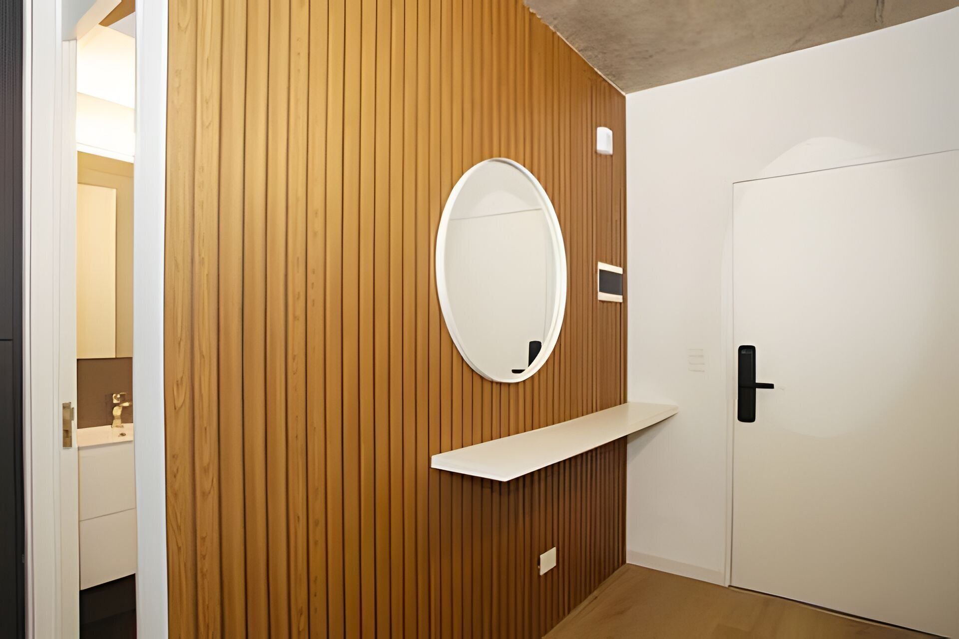 A room with a wooden panel wall, a white door, and a mirror on the wall.
