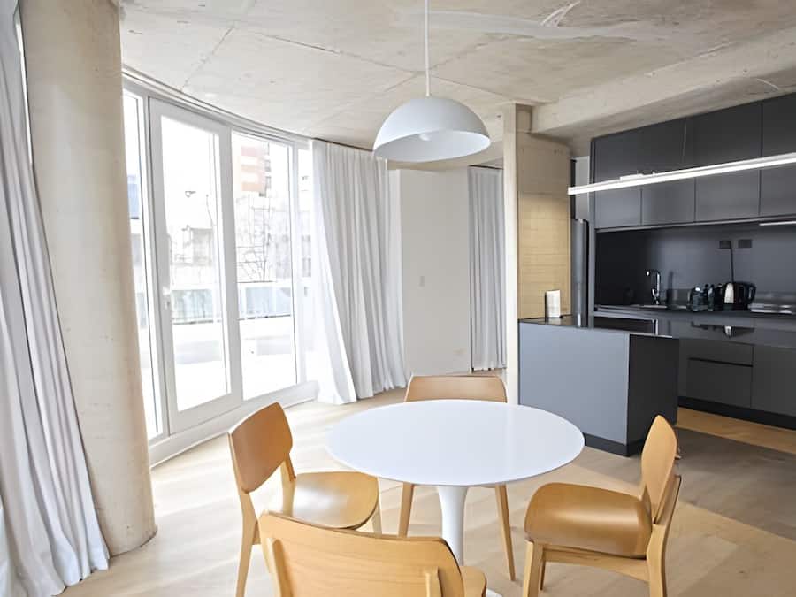 Una cocina moderna con gabinetes oscuros, una encimera blanca y una lámpara colgante.