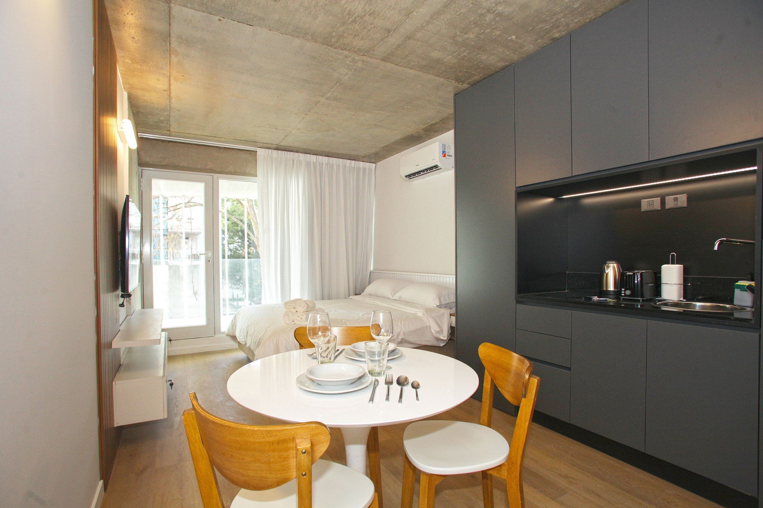 Habitació d'hotel senzilla amb zona de menjador, petita cuina i llit amb vistes.