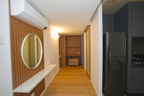 A narrow hallway with wooden paneling, a built-in bench, and a modern black refrigerator. - Urban Rent - Tu hogar temporario (Buenos Aires)