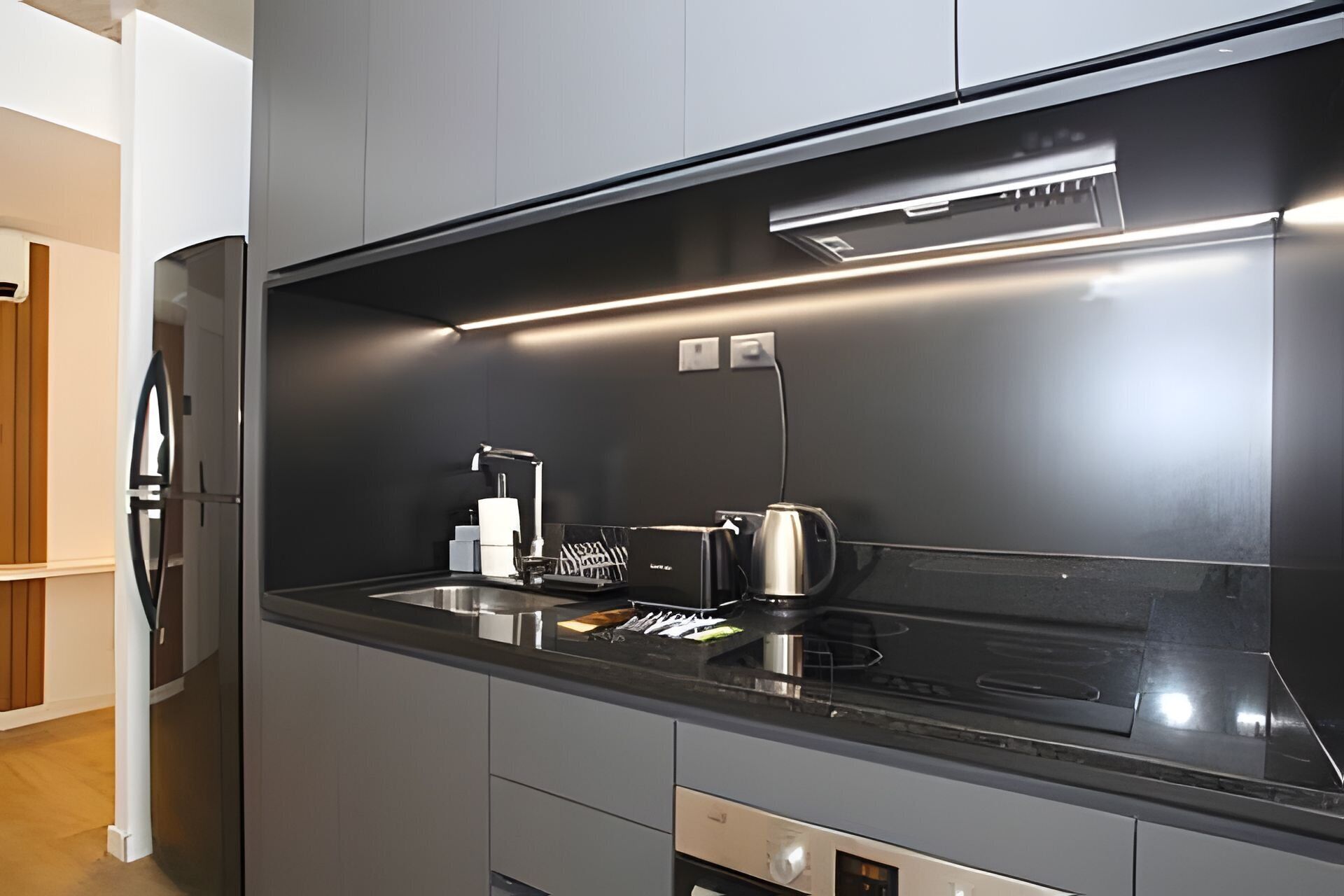 Una cocina moderna con cubierta negra, electrodomésticos de acero inoxidable y horno empotrado.
