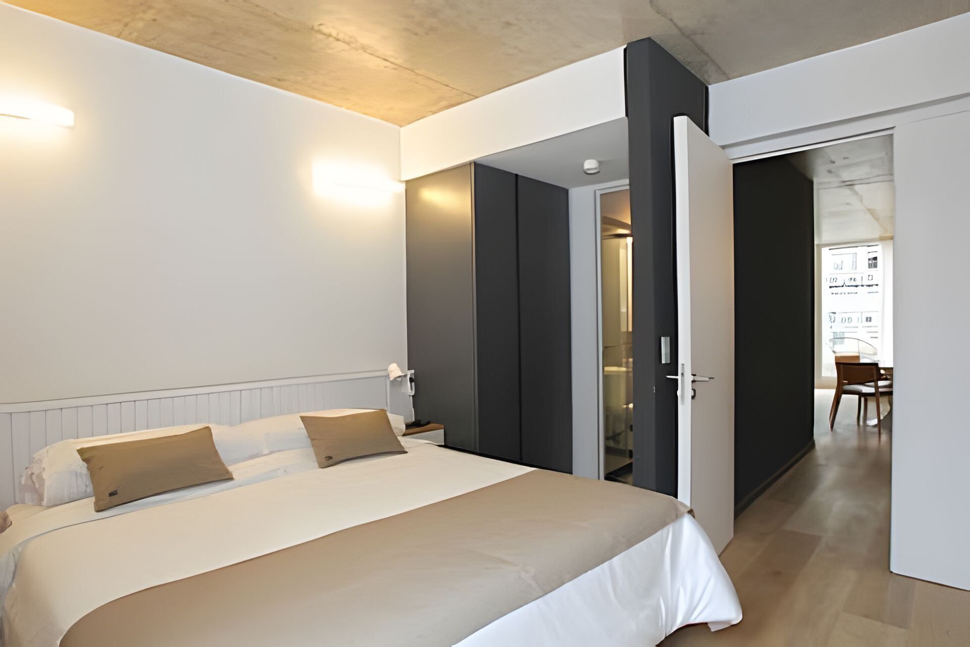 Un dormitorio moderno con una cama grande, mesitas de noche y un armario.