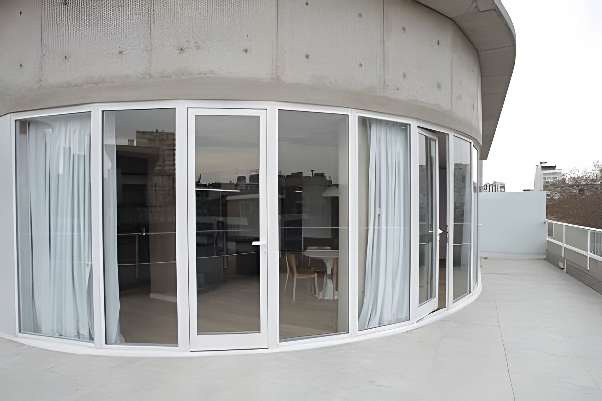 Une chambre d’angle dotée d’un balcon incurvé, de grandes portes vitrées et offrant une vue sur le paysage urbain.
