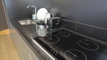 A modern kitchen with a black countertop, stainless steel sink, and a black induction cooktop with four burners.