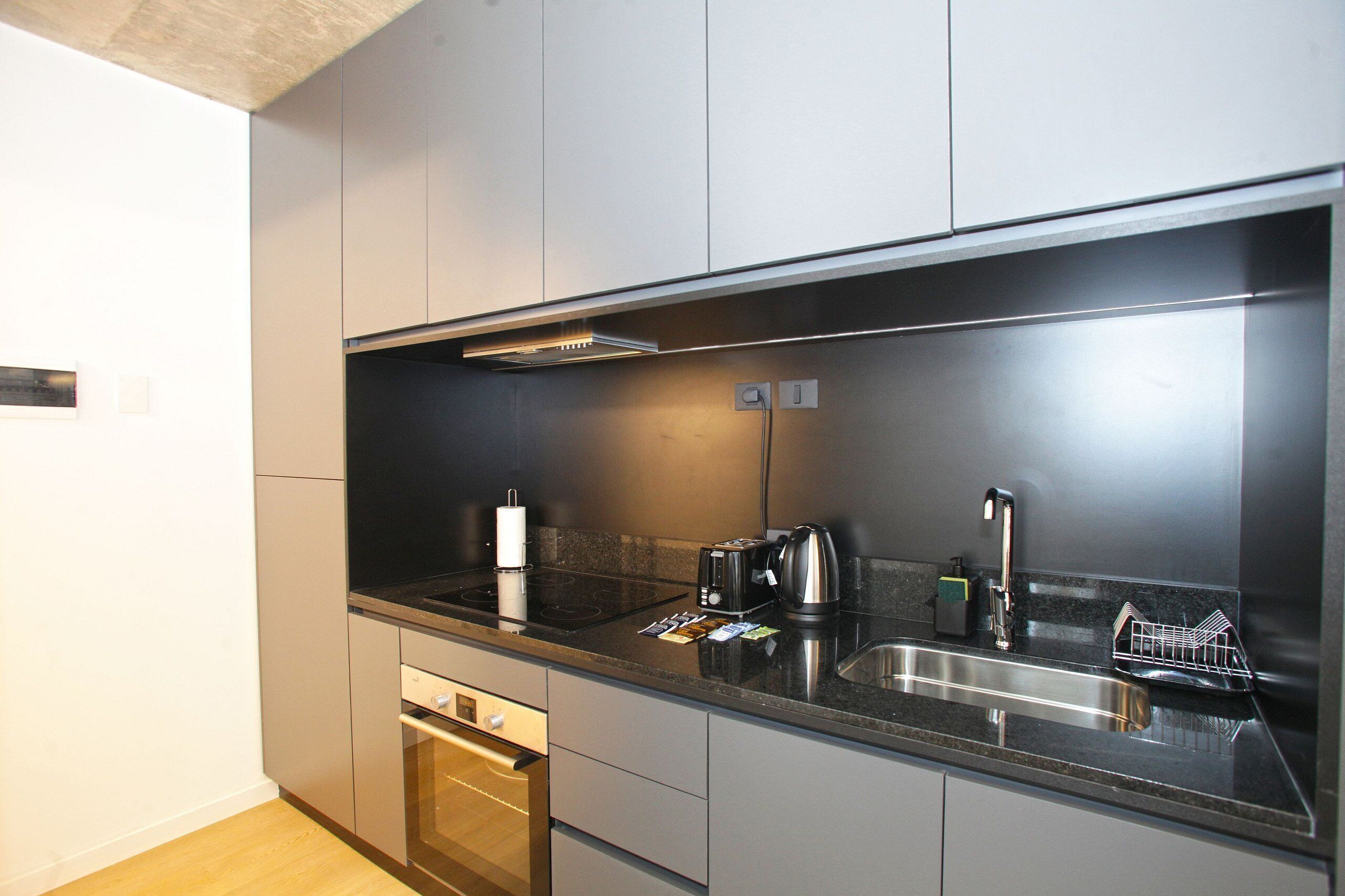 A modern kitchen with a stainless steel sink, a toaster, and a kettle.