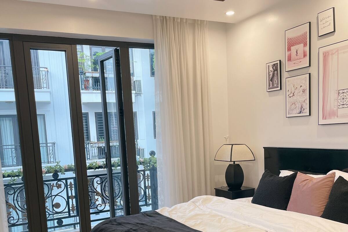 A bedroom with a bed, a nightstand, a lamp, and a view of the outside balcony.