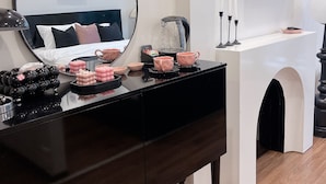 A modern bedroom with a large mirror, a flat-screen TV, a bedside table with decorative items, and a bed with a dark headboard. - C&K Luxury Homestay Hai Phong (Hai Phong)