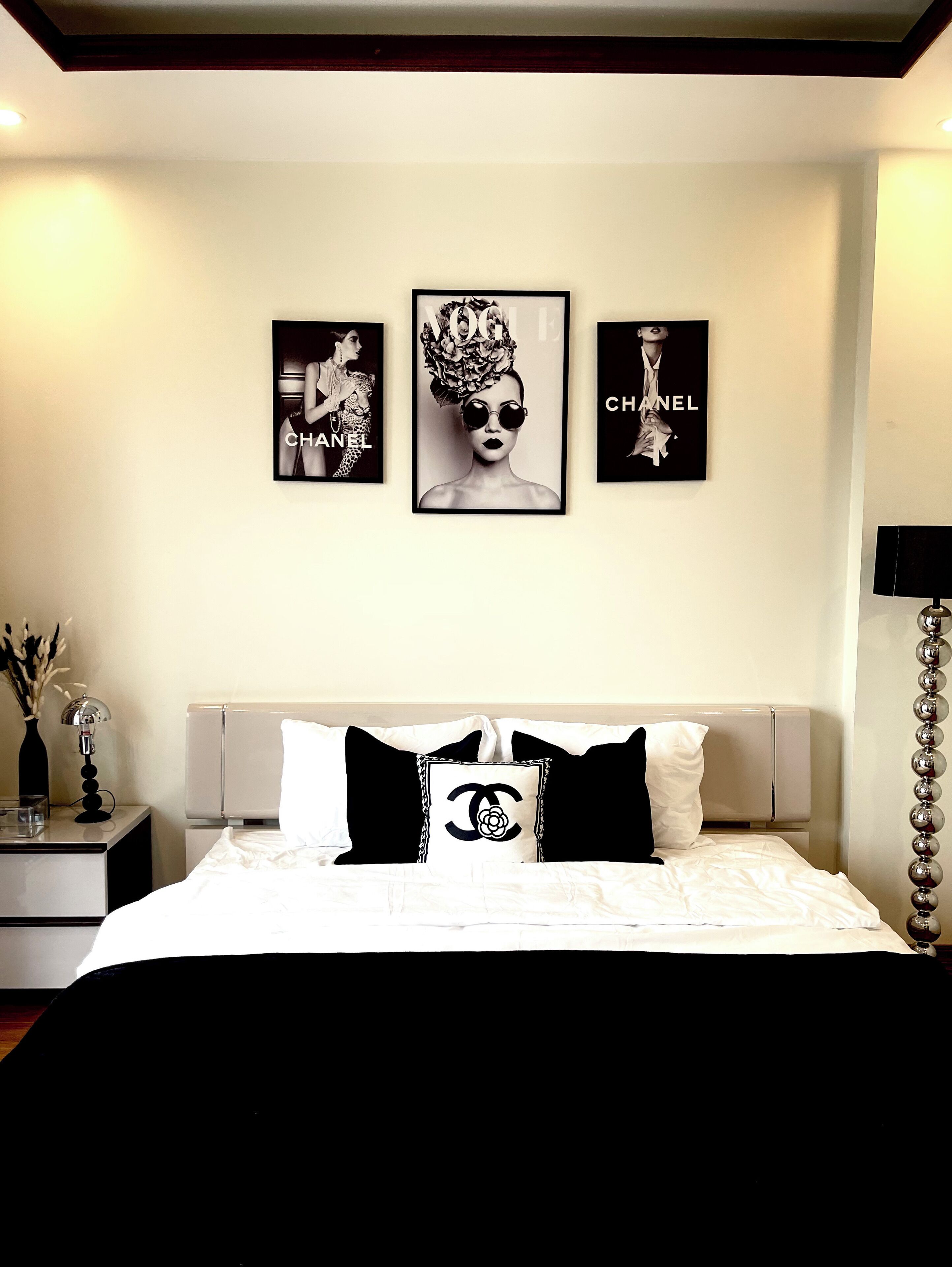 A bedroom with a bed, a nightstand, a lamp, and three framed pictures on the wall.