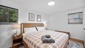 Een hotelkamer met een bed, twee nachtkastjes, een lamp en een raam met jaloezieën.