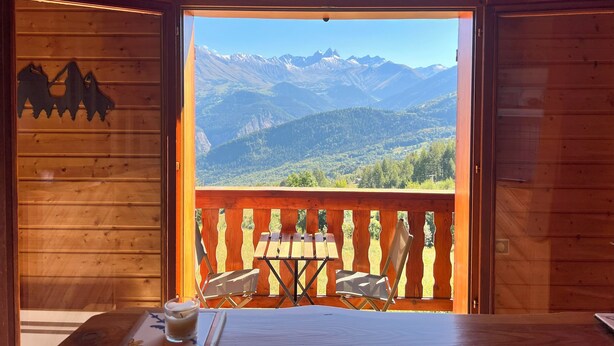A wooden cabin with a balcony overlooking a mountainous landscape.