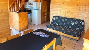 A wooden interior with a kitchenette, a dining table, and a sofa.