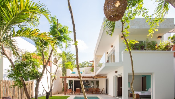 Ein modernes Haus mit Pool, Terrassenmöbeln und üppiger Bepflanzung.