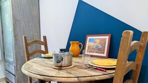 A round wooden dining table with a metal pot, a glass, and a yellow plate. - Studio Van Gogh - Air conditionning (Arles)