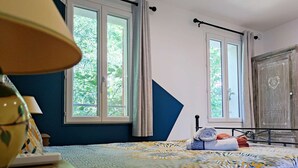 A bedroom with a bed, two windows, a lamp, and a wardrobe. - Studio Van Gogh - Air conditionning (Arles)
