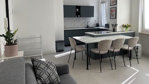 Una cocina moderna con una isla central, armarios grises y una zona de comedor con mesa y sillas.