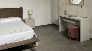 Un dormitorio con cama, escritorio, silla, radiador y espejo.
