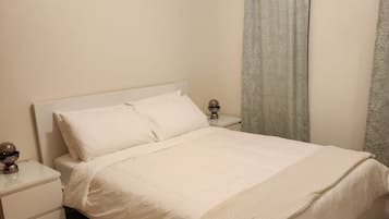 Quarto com cama, mesas de cabeceira, abajur e ar condicionado.
