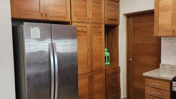 Eine Küche mit Holzausstattung, einem Edelstahl-Kühlschrank und einer Arbeitsplatte aus Granit.
