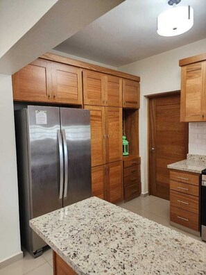 Eine Küche mit Holzausstattung, einem Edelstahl-Kühlschrank und einer Arbeitsplatte aus Granit.